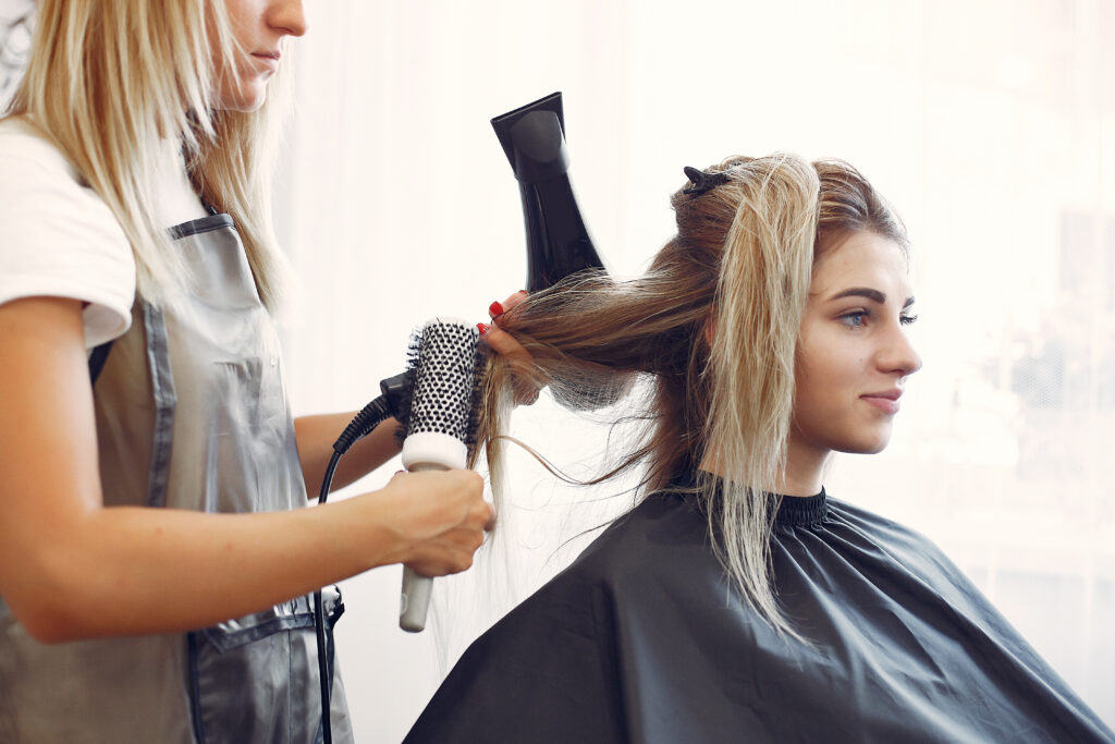 Hairdresser drying head her client. Woman in a hair salon