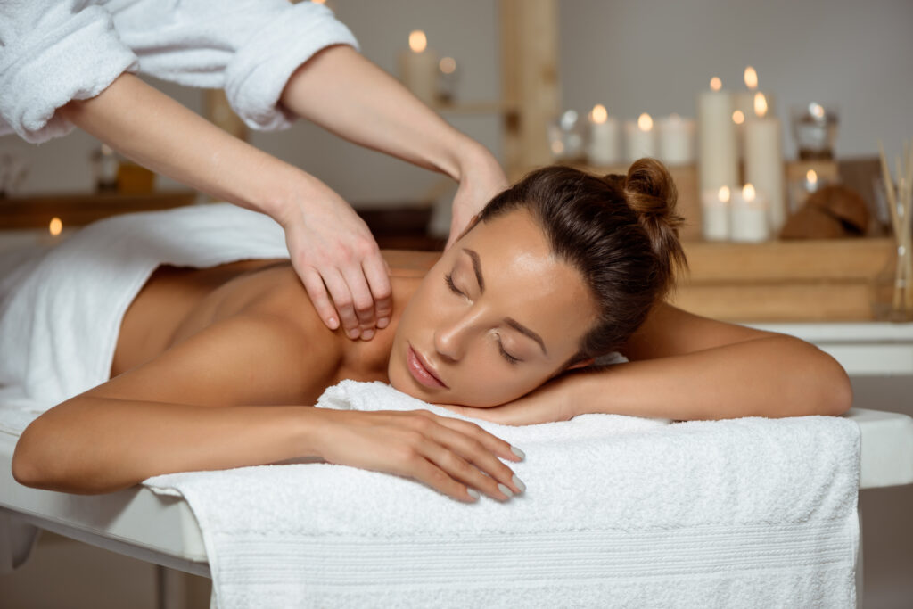 Young attractive brunette girl having massage relaxing in spa salon. Eyes closed. Copy space.
